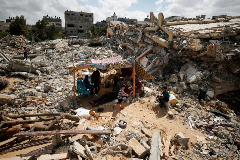 Palestinians sit in a makeshift tent amid the rubble of their houses which were destroyed by Israeli air strikes, Gaza, May 23, 2021