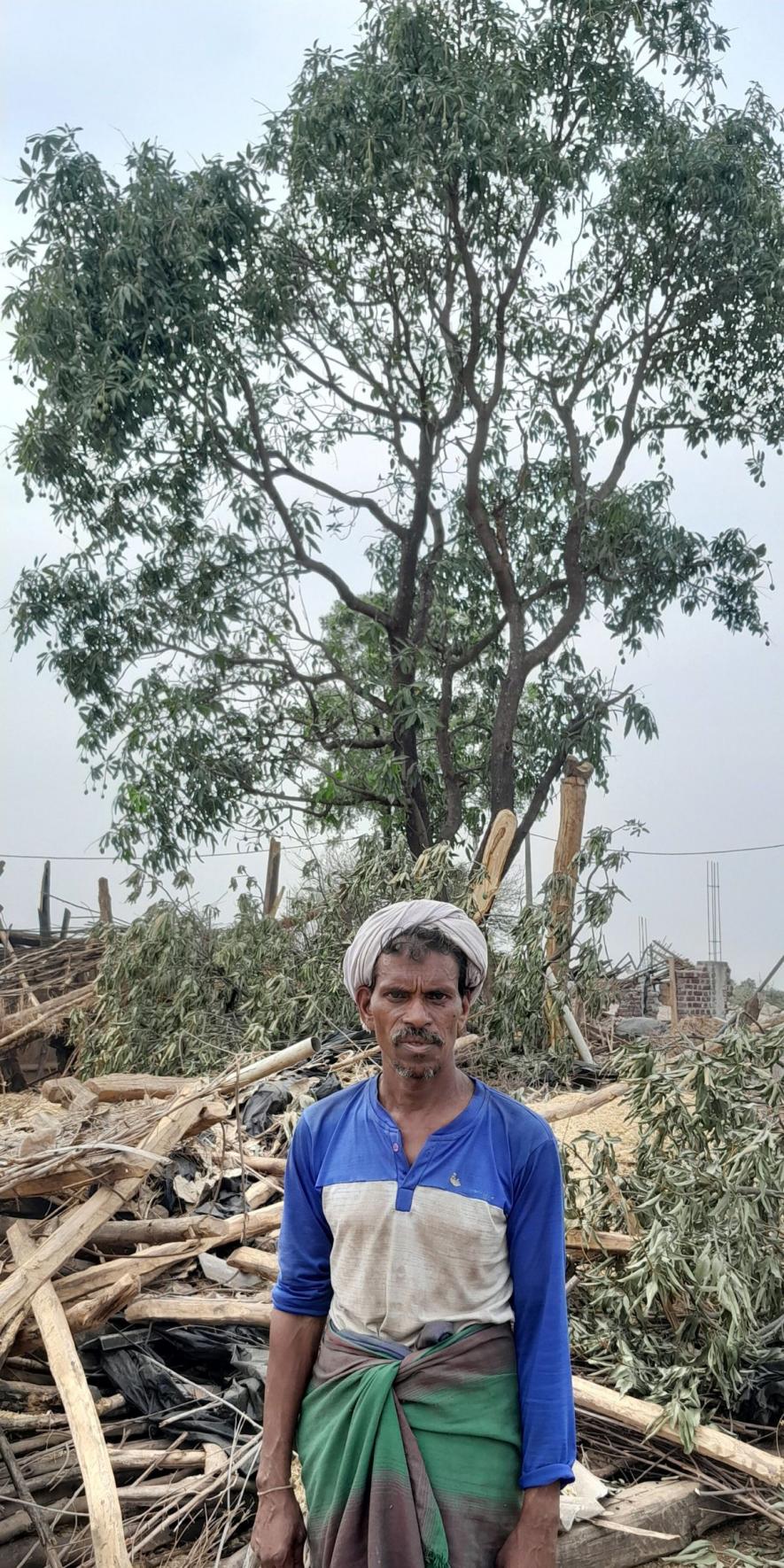 Standing in front of his gutted home, Vikram Gutram promises to rebuild. The mango tree behind him was planted and nurtured by him from seed (Photo - Mohammad Asif Siddiqui, 101Reporters).