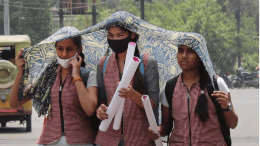 Students shield themselves from the heat with a scarf on a hot summer afternoon in Meerut, UP. Image Courtesy: PTI
