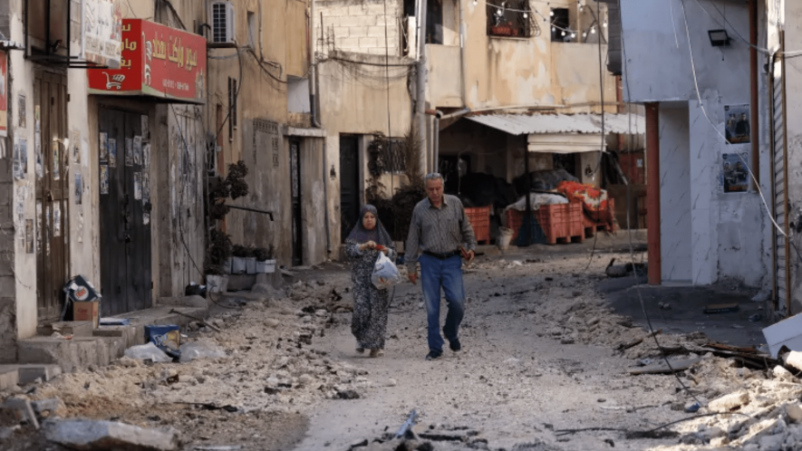 A couple walks in a street in the Jenin refugee camp. Image Courtesy [Ronaldo Schemidt/AFP]